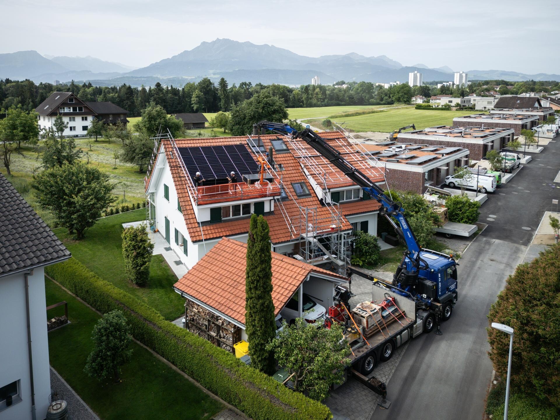 Einfamilienhaus mit neuer Photovoltaik-Anlage in einem Dorf der Zentralschweiz, davor der Kranwagen.