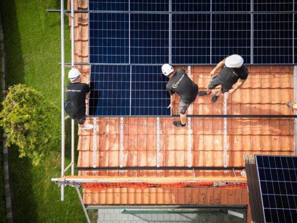 Aufsicht auf ein Ziegeldach: das Montageteam arbeitet an der neuen Photovoltaik-Anlage.